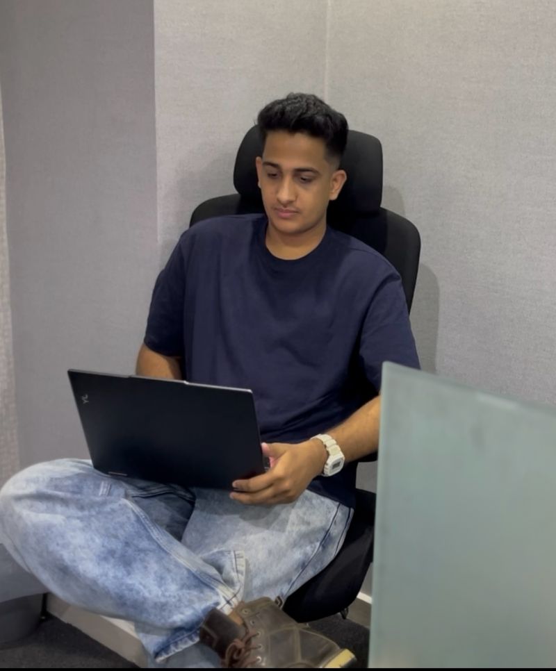 Photo of Muhammed Nasvih seated in an office chair, working on a laptop in a casual indoor setting.